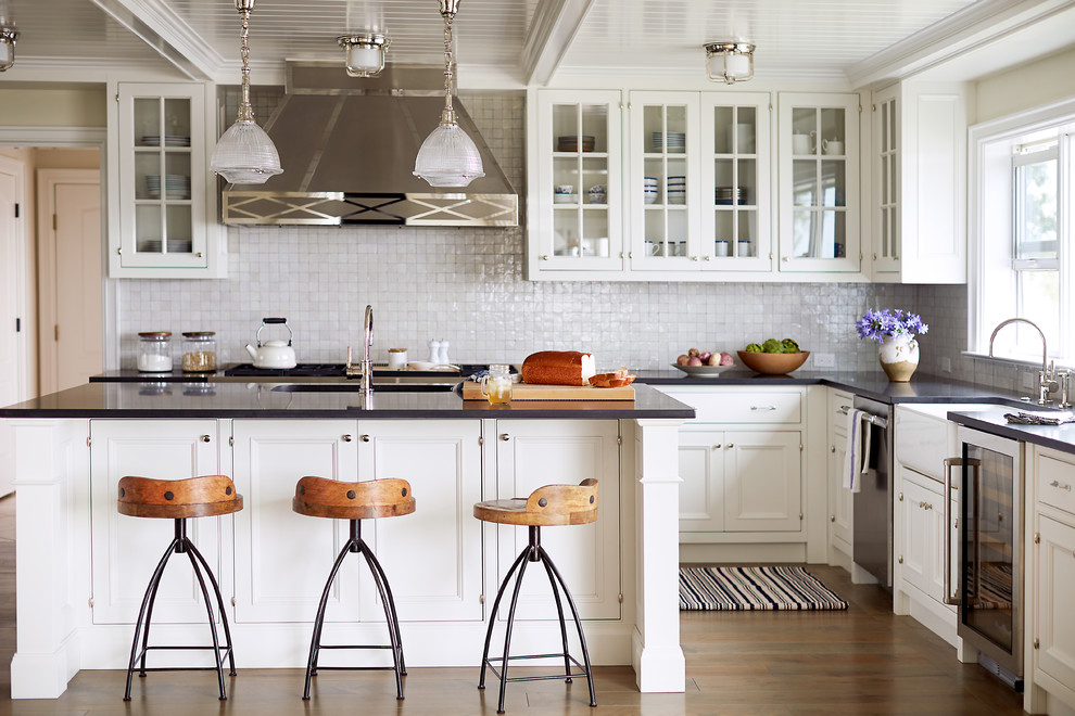 Inspiration for a traditional l-shaped kitchen in Jacksonville with a farmhouse sink, glass-front cabinets, white cabinets, grey splashback, stainless steel appliances, medium hardwood floors and with island.