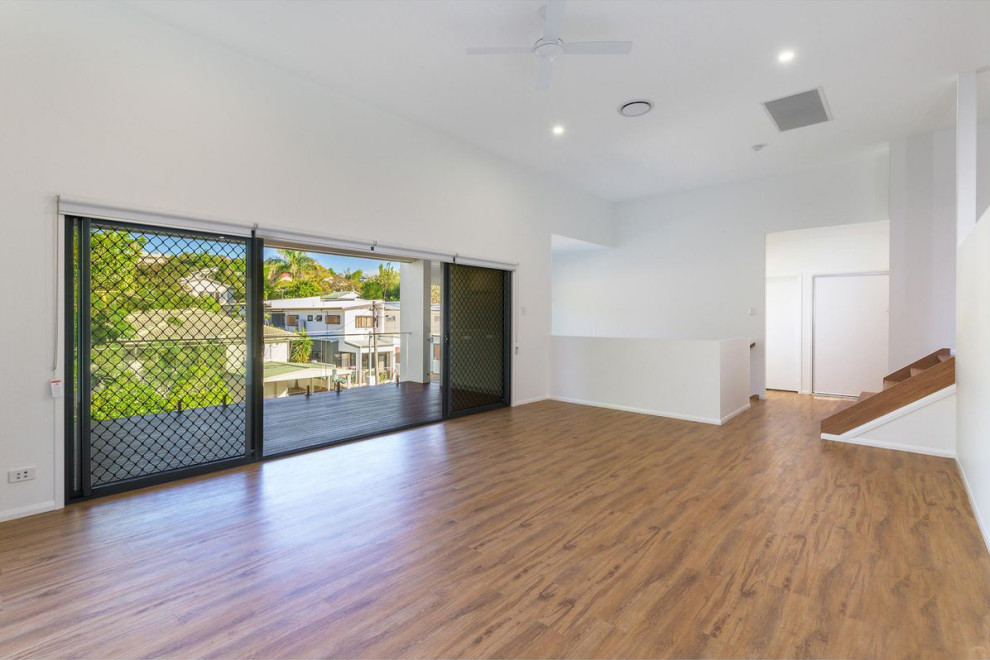 Photo of a mid-sized contemporary open concept living room in Brisbane with white walls, vinyl floors, a freestanding tv and beige floor.
