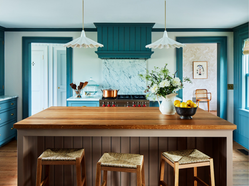 This is an example of a large beach style u-shaped eat-in kitchen in Boston with turquoise cabinets, stainless steel appliances, laminate floors, with island, white benchtop, beaded inset cabinets, white splashback, stone slab splashback and brown floor.