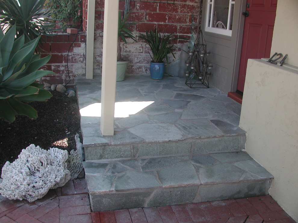 This is an example of a small arts and crafts front yard verandah in Los Angeles with a container garden, natural stone pavers and a roof extension.