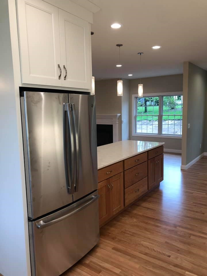 Example of a large transitional l-shaped medium tone wood floor kitchen design with an undermount sink, shaker cabinets, medium tone wood cabinets, quartz countertops, stainless steel appliances, a peninsula and white countertops