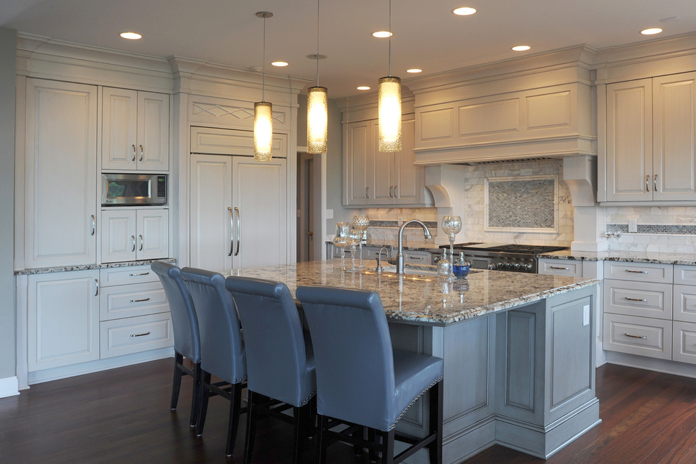 Example of a mid-sized transitional l-shaped dark wood floor open concept kitchen design with an undermount sink, raised-panel cabinets, white cabinets, granite countertops, white backsplash, mosaic tile backsplash, stainless steel appliances and an island