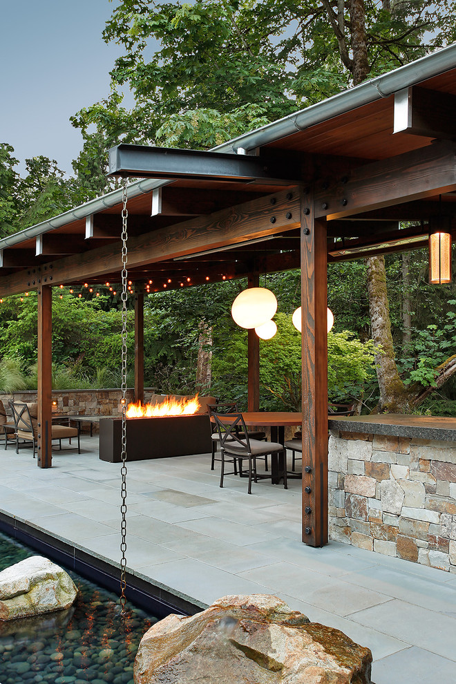 Photo of a country backyard patio in Seattle with concrete pavers and a fire feature.
