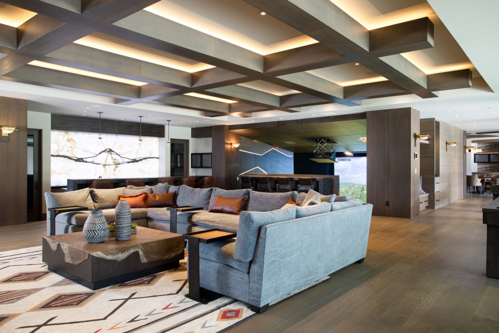 Example of a huge trendy open concept medium tone wood floor, brown floor, exposed beam and wood wall family room design in Salt Lake City with a bar, white walls, a standard fireplace, a stone fireplace and a media wall