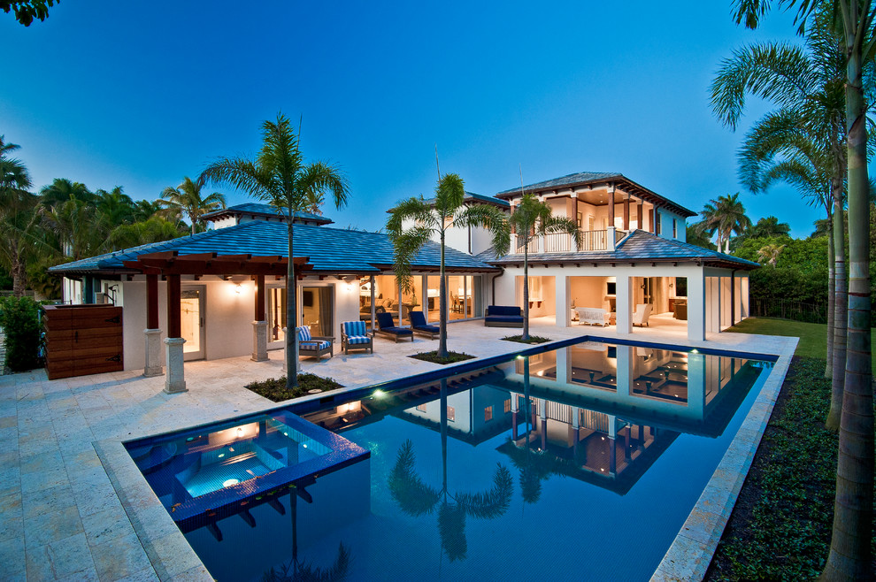 Large beach style backyard rectangular pool in Miami with tile.