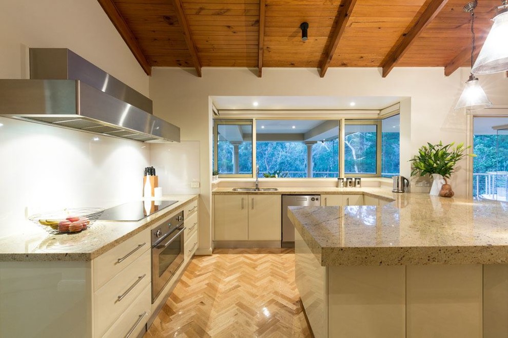 Contemporary kitchen in Other with a double-bowl sink, beige cabinets, granite benchtops, white splashback, stainless steel appliances and light hardwood floors.