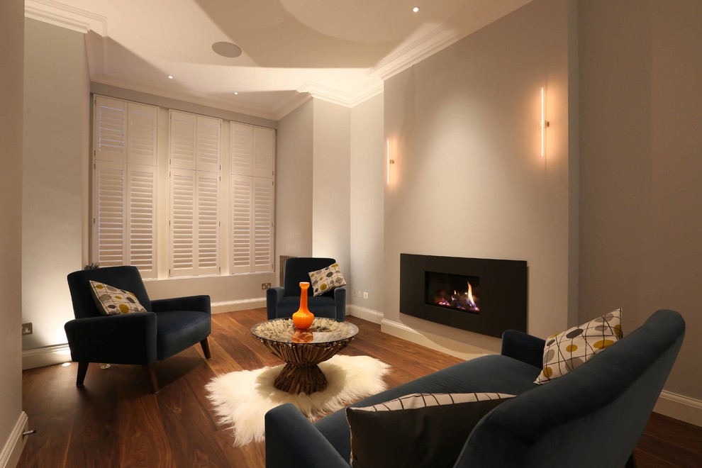 Photo of a mid-sized contemporary enclosed living room in London with white walls, dark hardwood floors, a ribbon fireplace and a metal fireplace surround.
