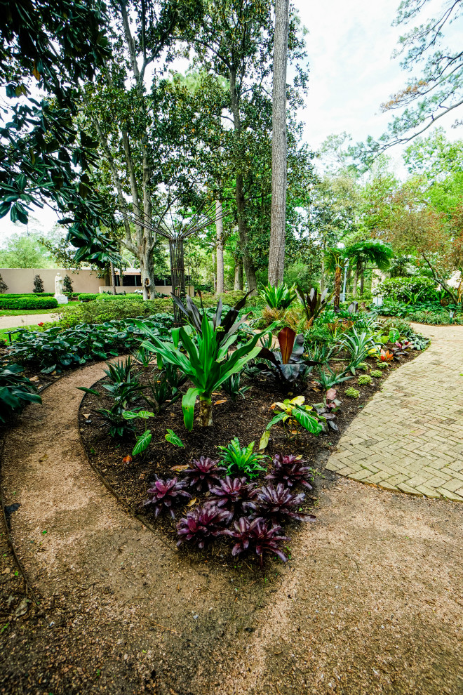 Inspiration for a mid-sized tropical backyard partial sun formal garden for spring in Houston with a garden path and brick pavers.