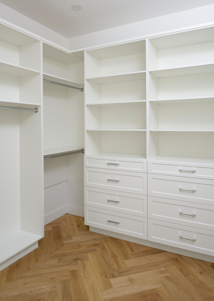 This is an example of a large country storage and wardrobe in Other with shaker cabinets, white cabinets, medium hardwood floors and exposed beam.