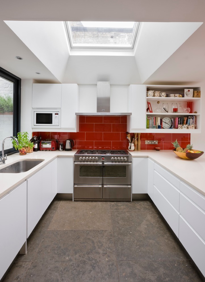 Inspiration for a mid-sized contemporary u-shaped kitchen in London with an undermount sink, flat-panel cabinets, white cabinets, quartzite benchtops, red splashback, glass tile splashback, stainless steel appliances, no island and marble floors.