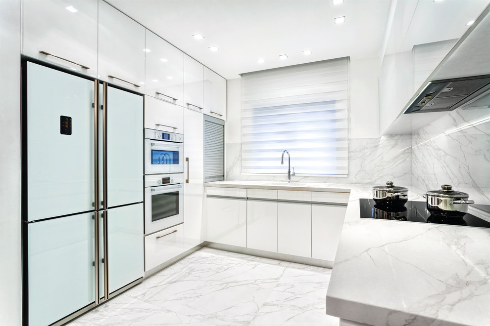 This is an example of a mid-sized modern u-shaped separate kitchen in Miami with an undermount sink, flat-panel cabinets, white cabinets, marble benchtops, marble splashback, stainless steel appliances and marble floors.