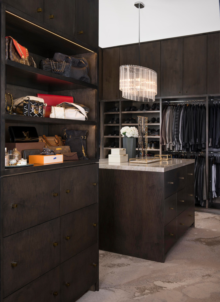 This is an example of a large contemporary gender-neutral walk-in wardrobe in Dallas with flat-panel cabinets, dark wood cabinets, carpet and beige floor.