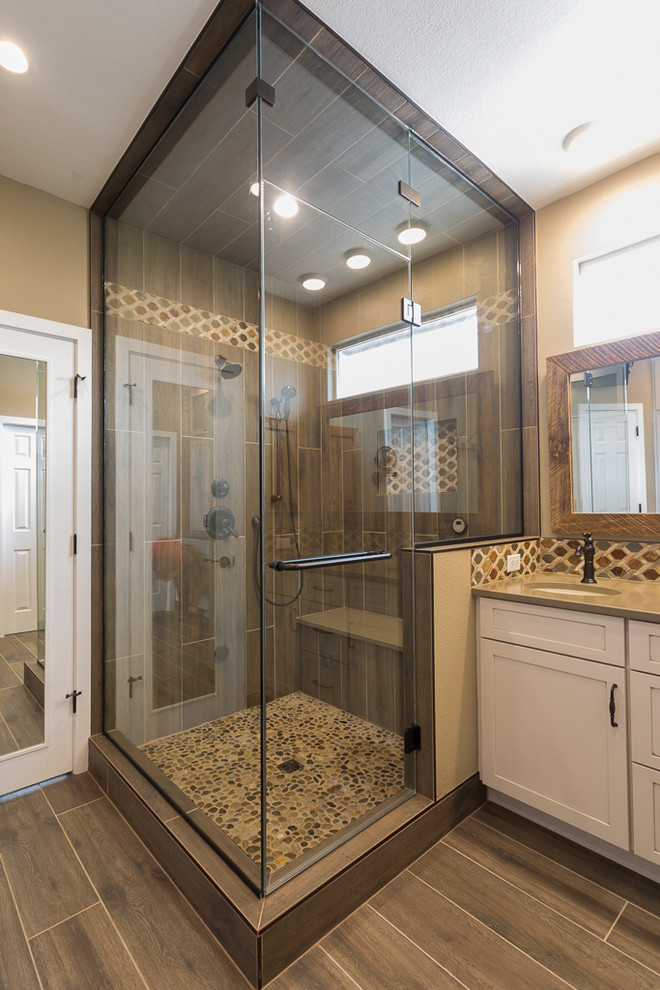 Example of a mid-sized mountain style master brown tile and porcelain tile porcelain tile and brown floor alcove shower design in Denver with shaker cabinets, beige cabinets, beige walls, an undermount sink, quartz countertops, a hinged shower door and brown countertops
