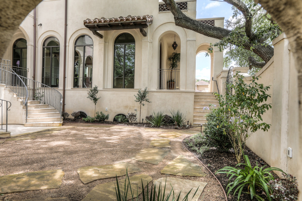 Large mediterranean two-storey stucco beige house exterior in Houston with a hip roof and a tile roof.