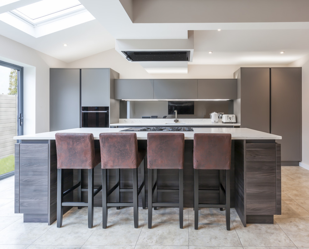 Mid-sized contemporary single-wall open plan kitchen in Manchester with an undermount sink, flat-panel cabinets, dark wood cabinets, quartzite benchtops, metallic splashback, panelled appliances, vinyl floors, with island, beige floor and white benchtop.