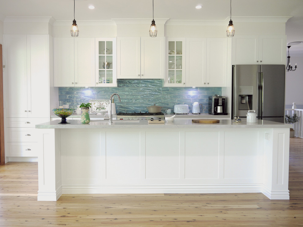 Design ideas for a large country galley eat-in kitchen in Sunshine Coast with an undermount sink, recessed-panel cabinets, white cabinets, quartz benchtops, blue splashback, ceramic splashback, stainless steel appliances, light hardwood floors, with island and grey benchtop.