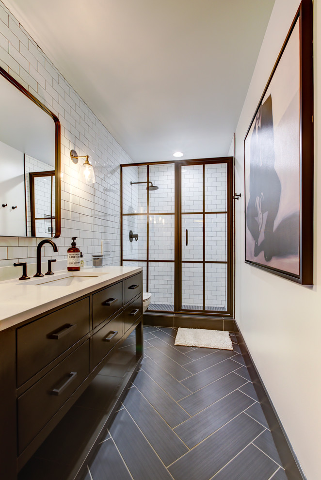 Design ideas for a mid-sized industrial bathroom in Raleigh with black cabinets, a wall-mount toilet, white tile, subway tile, white walls, porcelain floors, an undermount sink, engineered quartz benchtops, brown floor, a hinged shower door, an alcove shower and flat-panel cabinets.