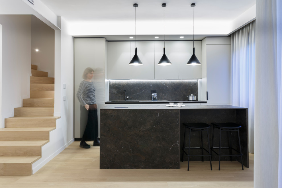 This is an example of a mid-sized modern galley eat-in kitchen in Rome with an integrated sink, flat-panel cabinets, beige cabinets, quartzite benchtops, brown splashback, engineered quartz splashback, stainless steel appliances, light hardwood floors, with island and brown benchtop.