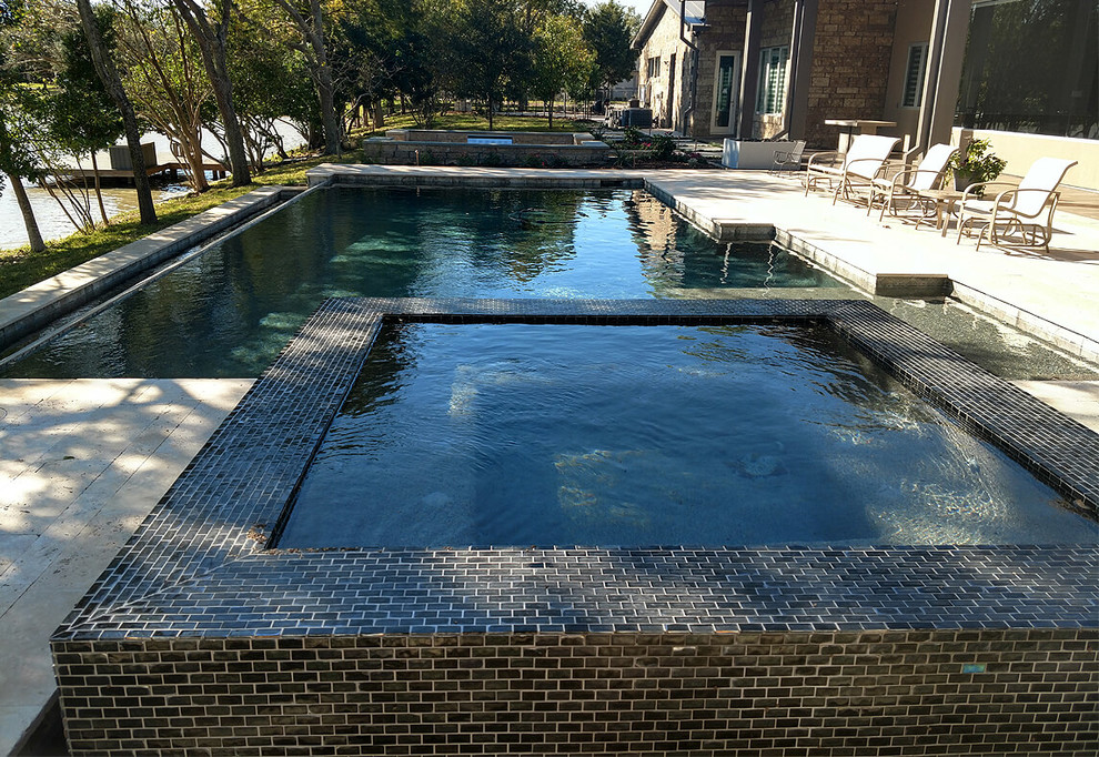 Modelo de piscinas y jacuzzis naturales de estilo americano grandes a medida en patio trasero con adoquines de piedra natural