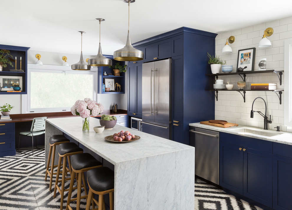 Design ideas for a transitional l-shaped kitchen in Seattle with an undermount sink, shaker cabinets, blue cabinets, white splashback, subway tile splashback, stainless steel appliances, cement tiles, with island, multi-coloured floor and white benchtop.