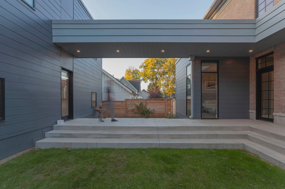 Mittelgroßes, Zweistöckiges Modernes Einfamilienhaus mit Faserzement-Fassade, grauer Fassadenfarbe, Flachdach und Verschalung in Indianapolis