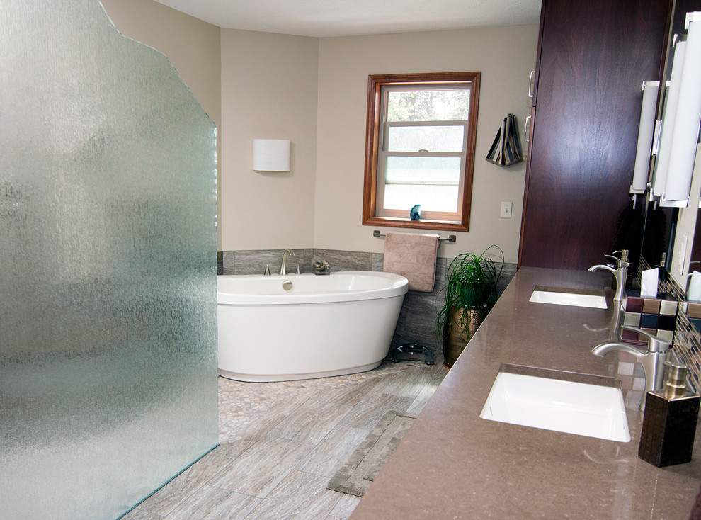 Large mountain style master brown tile and porcelain tile porcelain tile freestanding bathtub photo in Seattle with shaker cabinets, dark wood cabinets, a one-piece toilet, beige walls, an undermount sink and quartz countertops