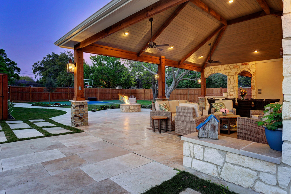 Design ideas for a large traditional backyard patio in Houston with an outdoor kitchen, natural stone pavers and a roof extension.
