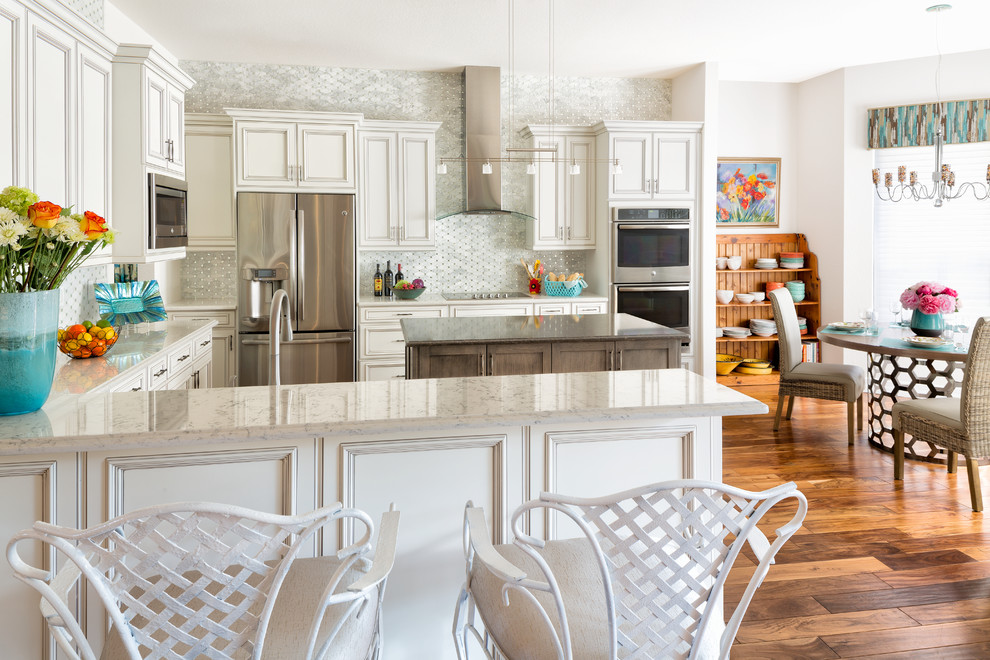 Eat-in kitchen - large transitional u-shaped dark wood floor and brown floor eat-in kitchen idea in Miami with a drop-in sink, recessed-panel cabinets, white cabinets, granite countertops, white backsplash, ceramic backsplash, stainless steel appliances and an island