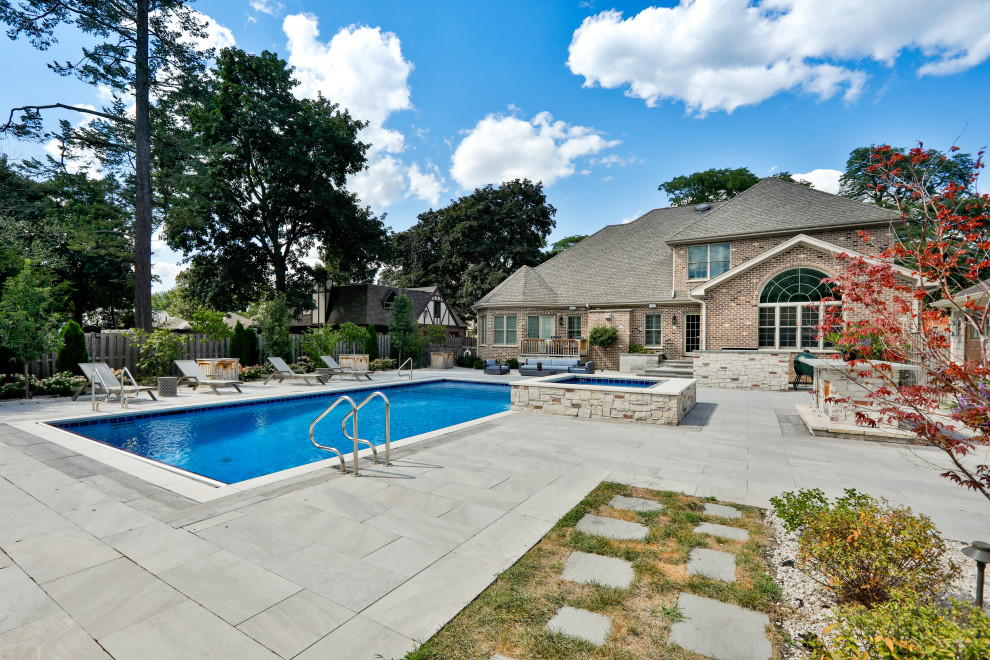 This is an example of a mid-sized traditional backyard rectangular lap pool in Chicago with with a pool and natural stone pavers.