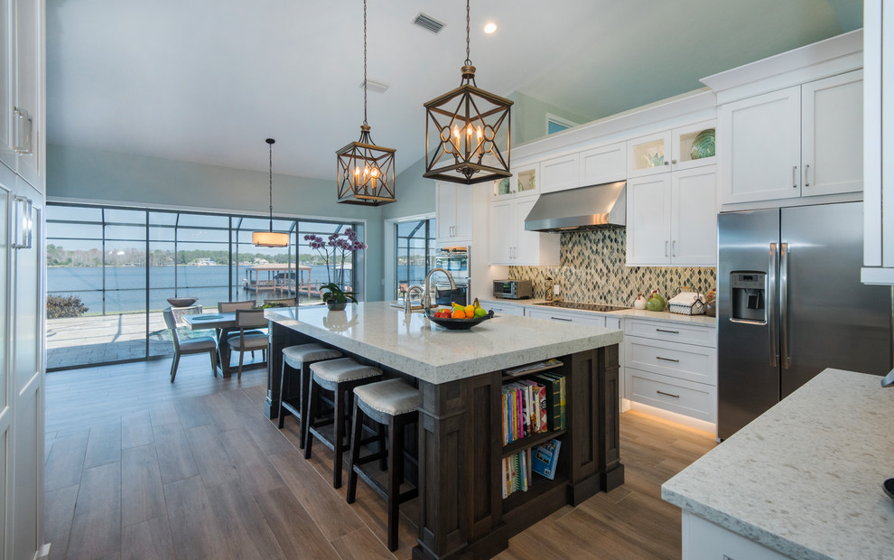 This is an example of a large transitional l-shaped eat-in kitchen in Orlando with an undermount sink, shaker cabinets, white cabinets, quartzite benchtops, multi-coloured splashback, glass tile splashback, stainless steel appliances, medium hardwood floors, with island and brown floor.