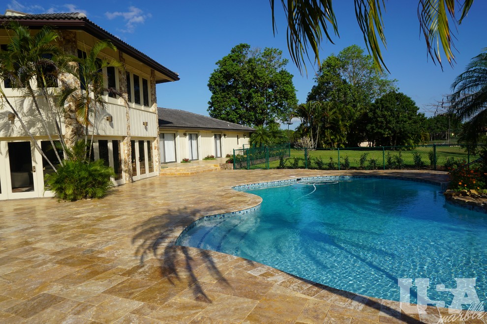 Photo of a large country backyard custom-shaped aboveground pool in Miami with natural stone pavers.