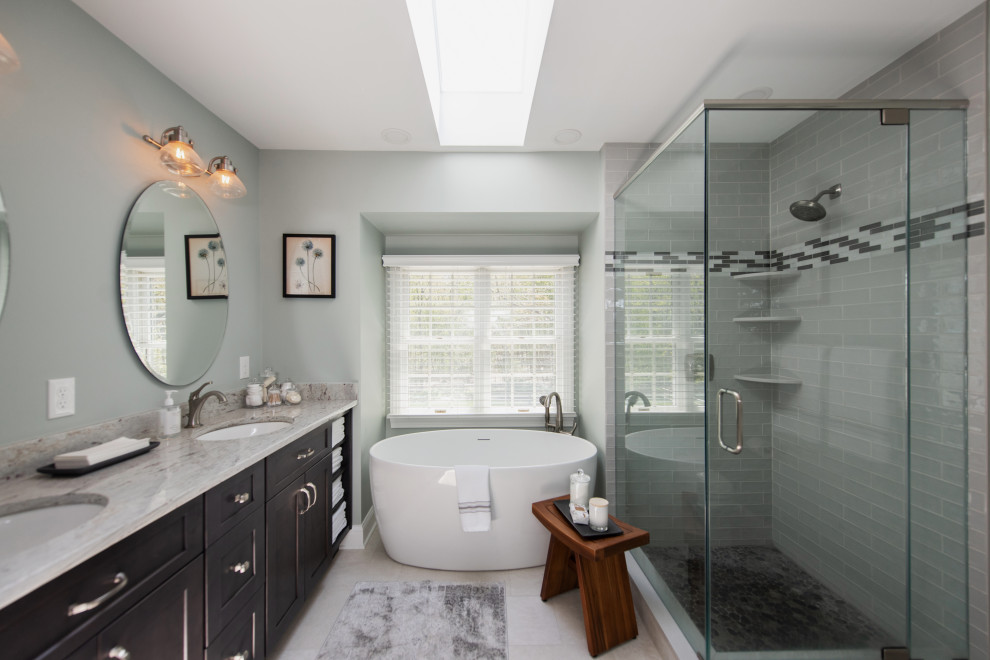 Design ideas for a mid-sized transitional master bathroom in Philadelphia with shaker cabinets, grey cabinets, a freestanding tub, a corner shower, a two-piece toilet, gray tile, ceramic tile, green walls, porcelain floors, an undermount sink, granite benchtops, grey floor, a hinged shower door, white benchtops, a double vanity and a built-in vanity.