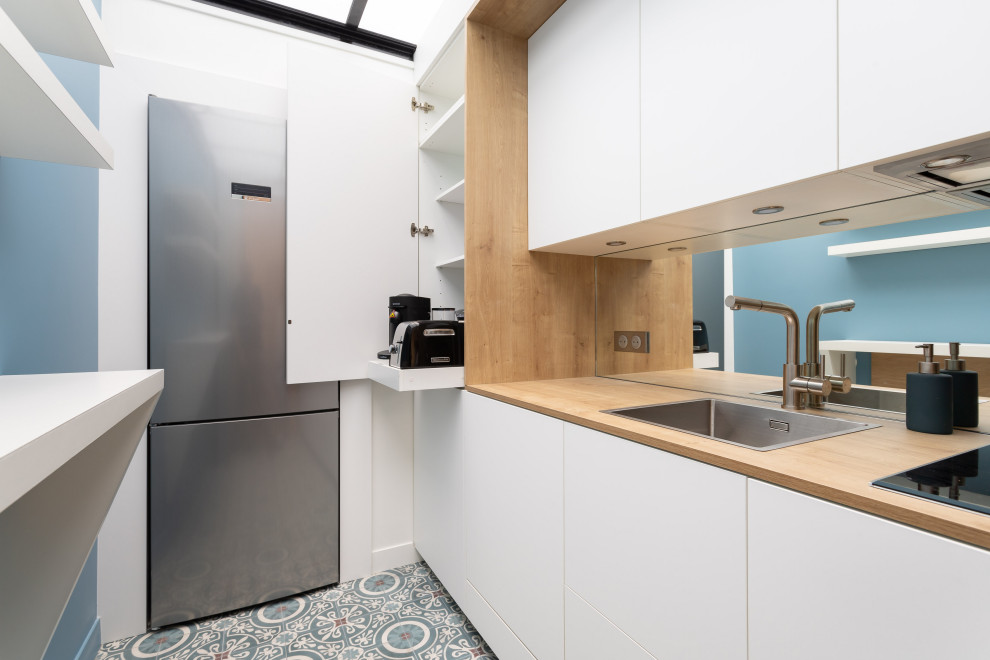 Photo of a small transitional single-wall separate kitchen in Paris with an undermount sink, beaded inset cabinets, white cabinets, wood benchtops, stainless steel appliances, cement tiles, blue floor and beige benchtop.