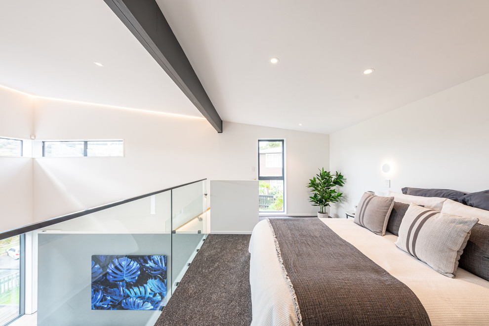 クライストチャーチにある中くらいなインダストリアルスタイルのおしゃれなロフト寝室 (白い壁、カーペット敷き、グレーの床、三角天井) のレイアウト
