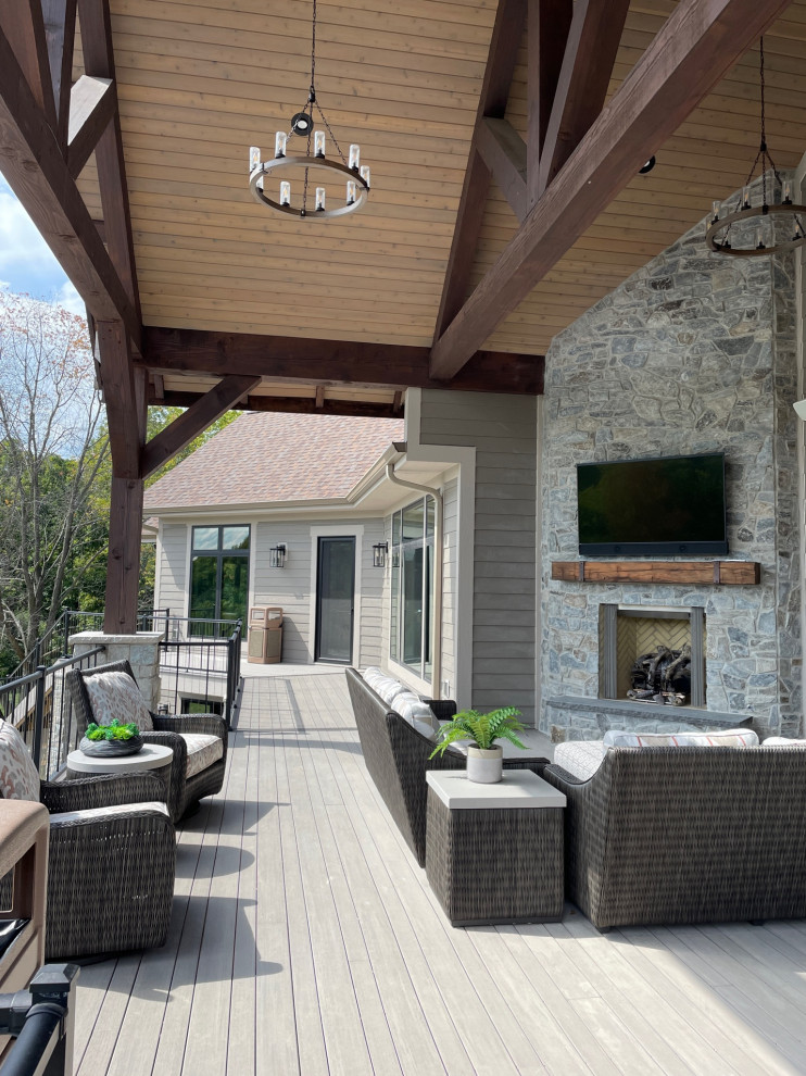 Photo of an expansive modern backyard and first floor deck in Milwaukee with with fireplace, a roof extension and metal railing.