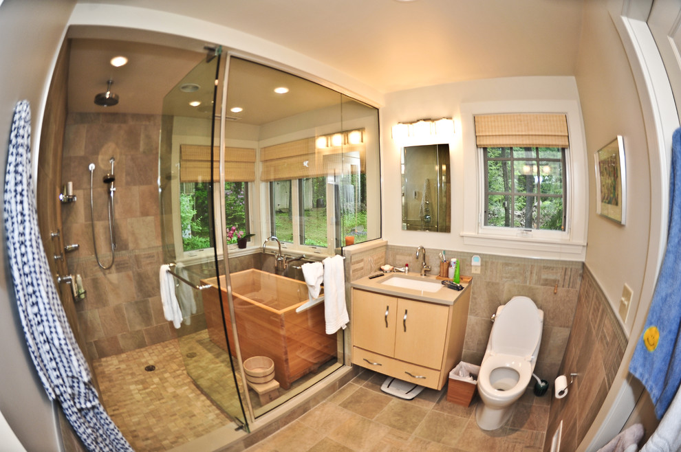 Immagine di un'ampia stanza da bagno padronale design con vasca giapponese, doccia doppia, ante in legno chiaro, top in legno, WC monopezzo, piastrelle in pietra e lavabo sottopiano