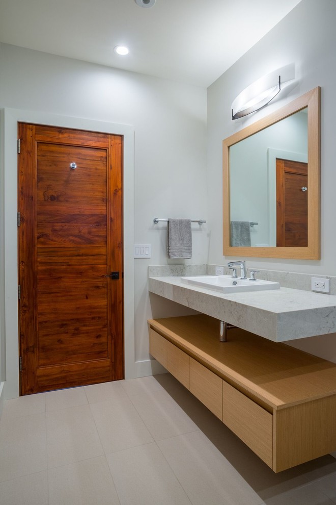This is an example of a mid-sized contemporary 3/4 bathroom in Hawaii with flat-panel cabinets, light wood cabinets, white walls, porcelain floors, a drop-in sink, engineered quartz benchtops and beige floor.