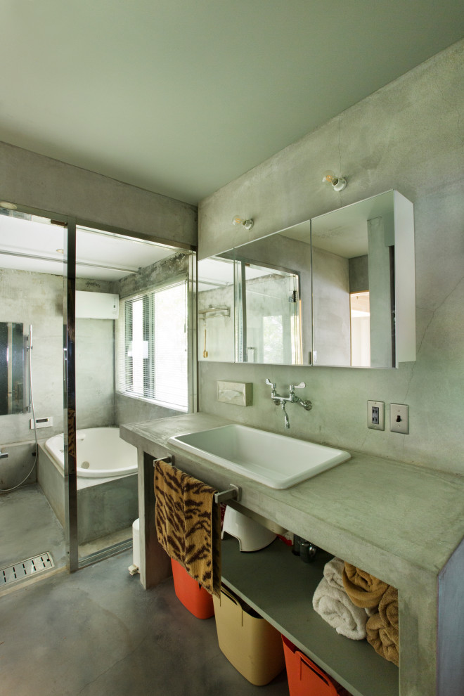 Inredning av ett modernt litet grå grått en-suite badrum, med öppna hyllor, grå skåp, ett platsbyggt badkar, våtrum, en toalettstol med hel cisternkåpa, grå väggar, betonggolv, ett undermonterad handfat, bänkskiva i betong, grått golv och med dusch som är öppen