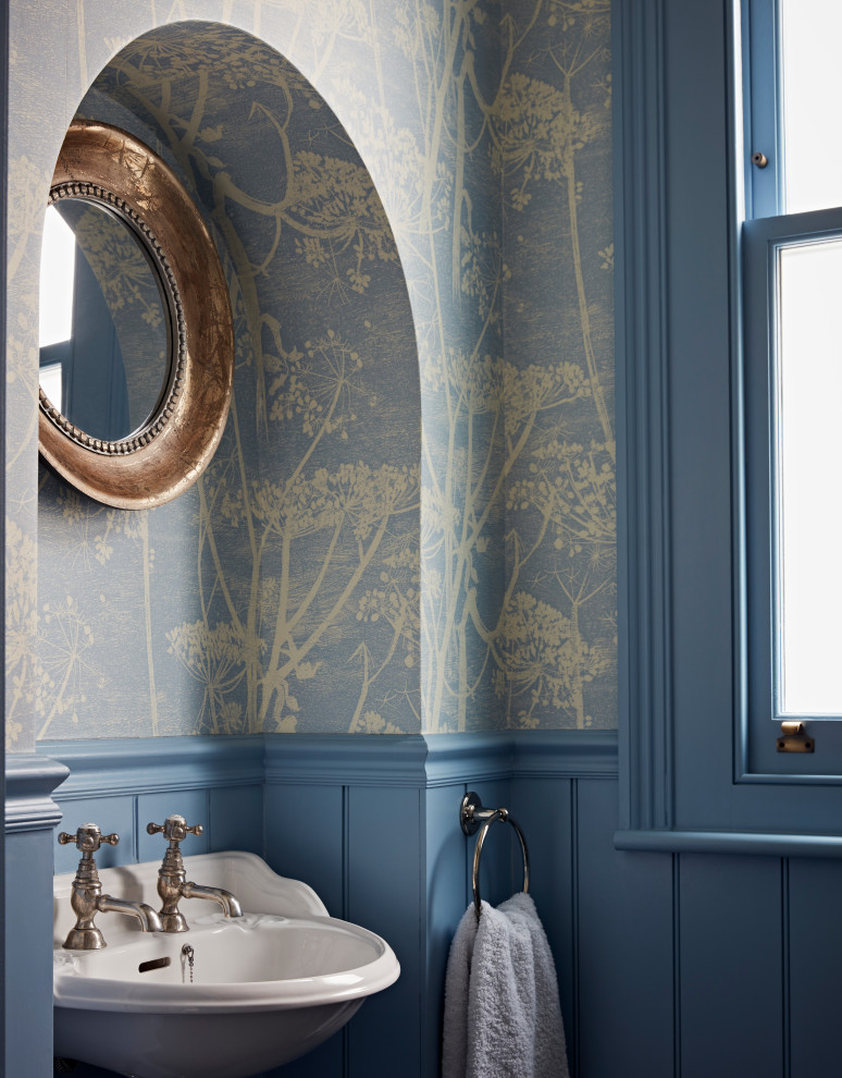 Example of a small transitional wall paneling powder room design in London with blue walls and a pedestal sink