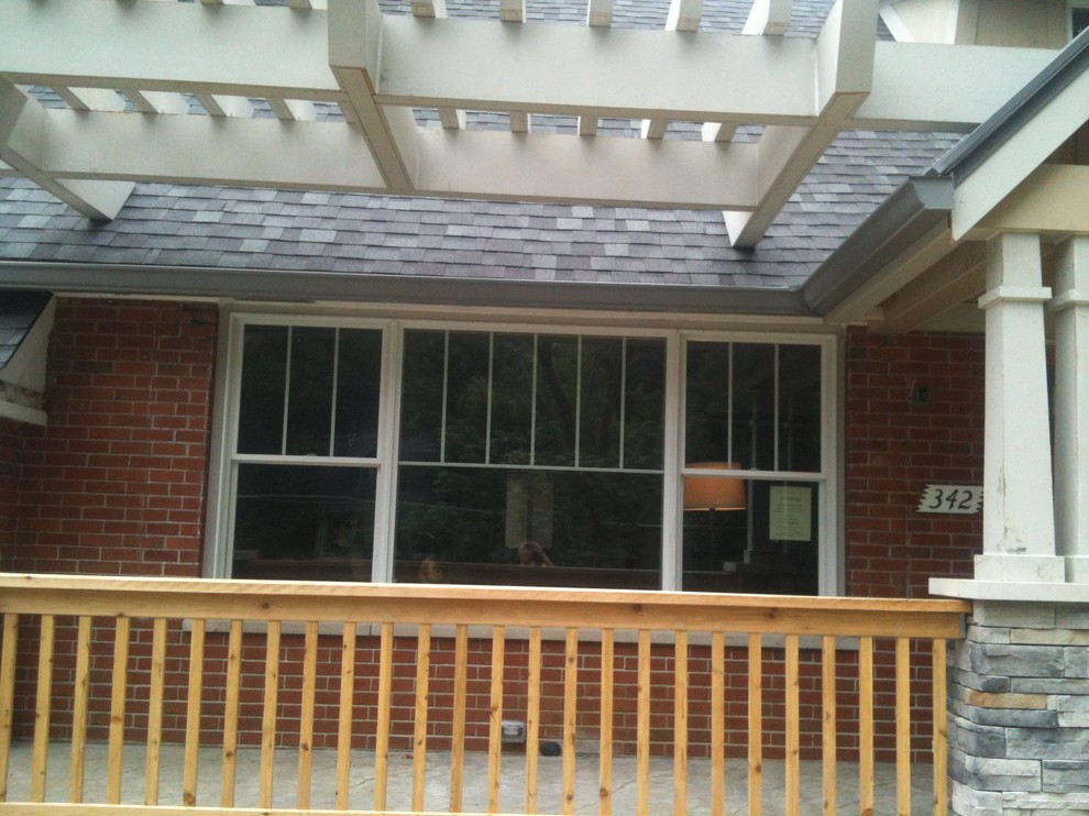 This is an example of a mid-sized traditional front yard verandah in St Louis with natural stone pavers and a pergola.