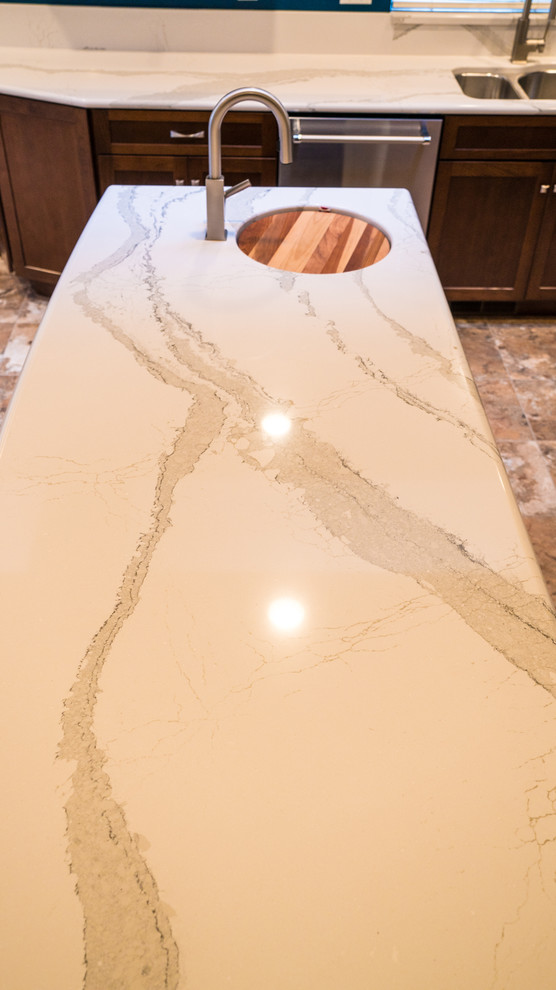 Example of a large transitional l-shaped laminate floor eat-in kitchen design in Seattle with an undermount sink, recessed-panel cabinets, dark wood cabinets, quartz countertops, stainless steel appliances and an island