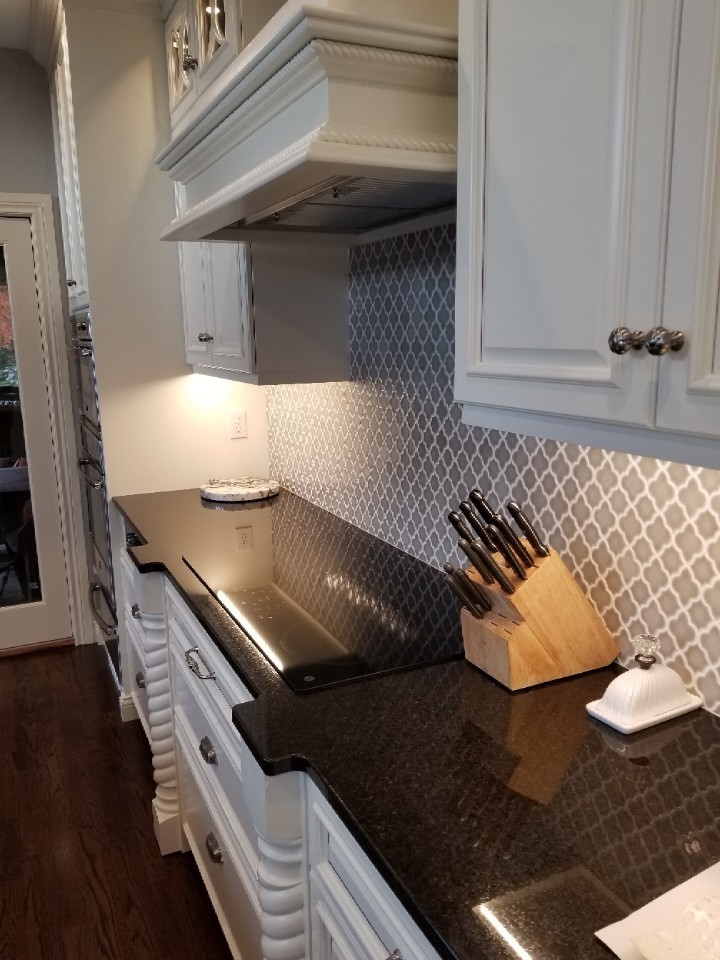 Eat-in kitchen - large transitional single-wall medium tone wood floor and brown floor eat-in kitchen idea with an undermount sink, raised-panel cabinets, white cabinets, granite countertops, gray backsplash, porcelain backsplash, stainless steel appliances, an island and black countertops