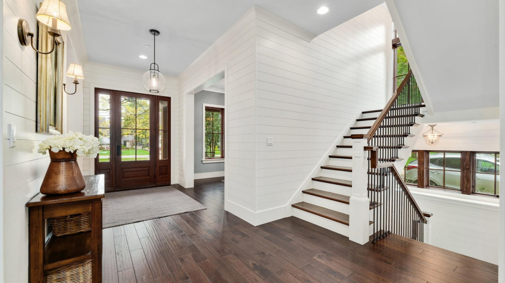 Expansive country foyer in Chicago with white walls, medium hardwood floors, a single front door, a medium wood front door, brown floor, timber and planked wall panelling.