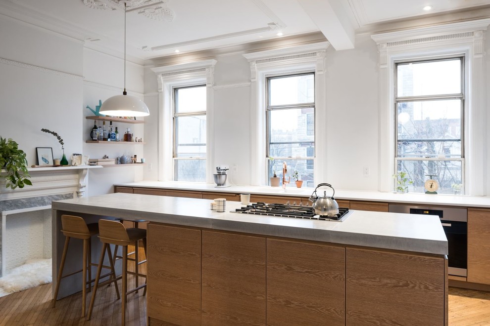 This is an example of a mid-sized contemporary single-wall separate kitchen in New York with a double-bowl sink, flat-panel cabinets, light wood cabinets, concrete benchtops, white splashback, stainless steel appliances, light hardwood floors and with island.