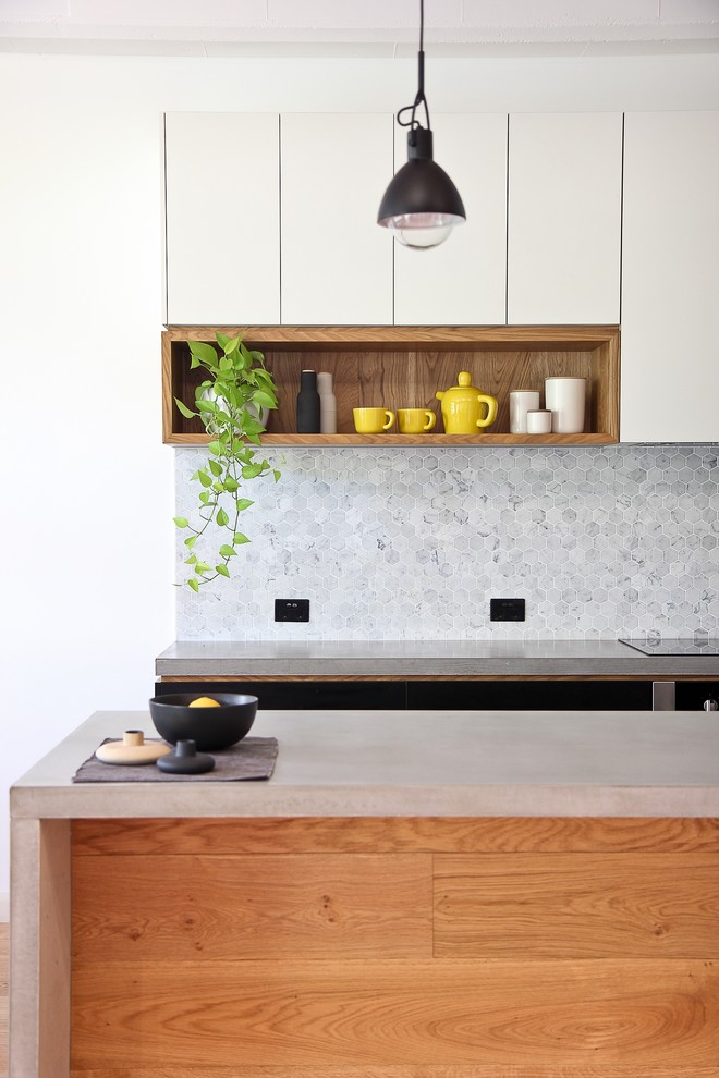 Photo of a mid-sized industrial galley kitchen in Brisbane with an integrated sink, concrete benchtops, grey splashback, stone tile splashback, light hardwood floors and with island.