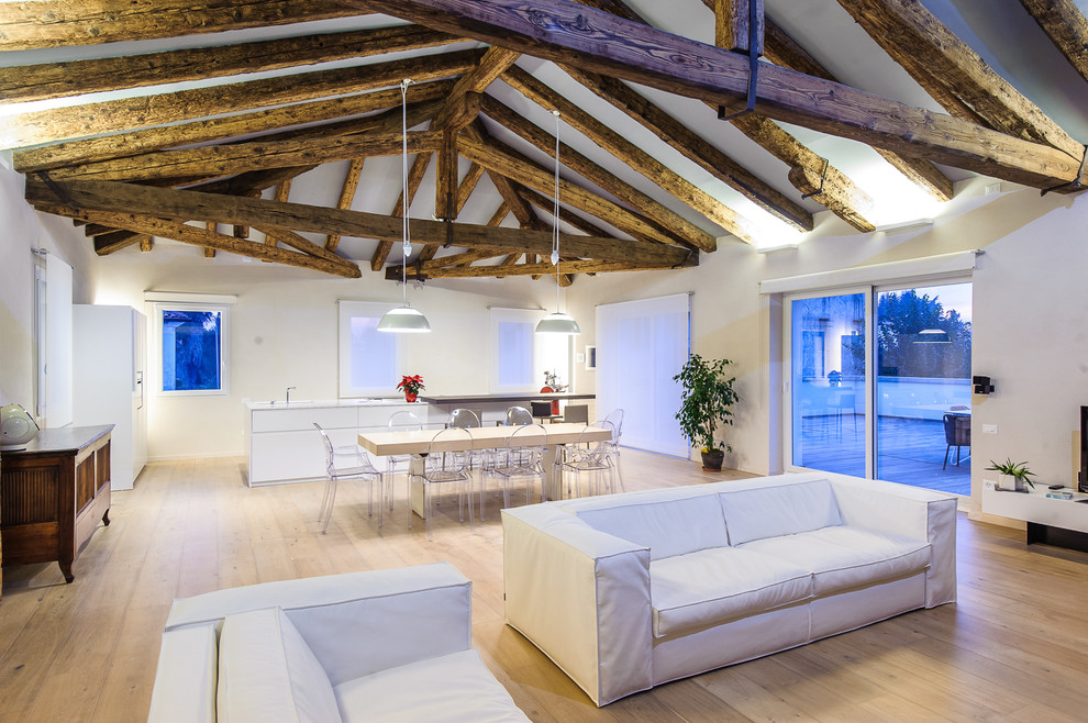 This is an example of an expansive contemporary open concept living room in Venice with white walls and light hardwood floors.