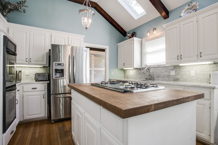 Mid-sized transitional u-shaped separate kitchen in Dallas with an undermount sink, raised-panel cabinets, white cabinets, wood benchtops, grey splashback, subway tile splashback, stainless steel appliances, medium hardwood floors and with island.
