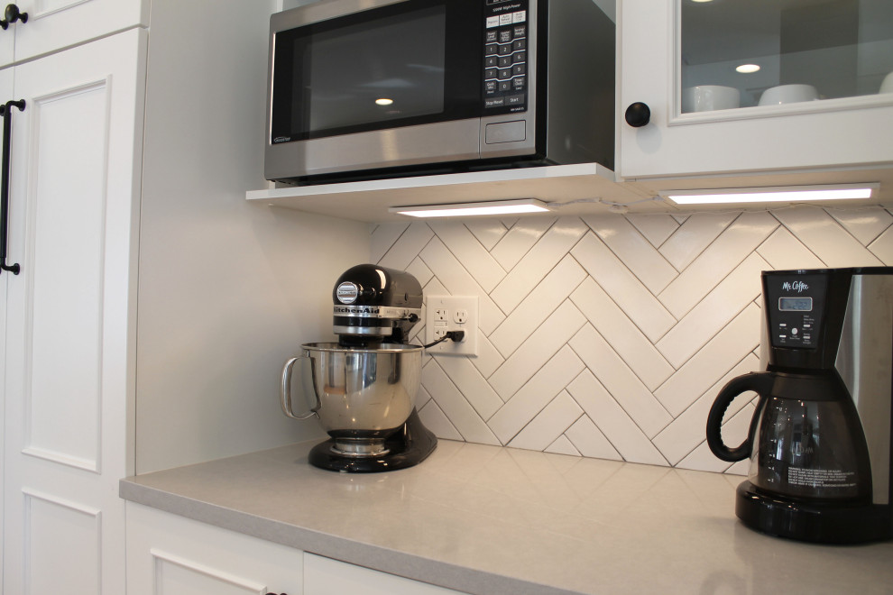 Eat-in kitchen - mid-sized transitional u-shaped medium tone wood floor eat-in kitchen idea in Seattle with an undermount sink, shaker cabinets, white cabinets, quartz countertops, white backsplash, ceramic backsplash, stainless steel appliances, a peninsula and gray countertops