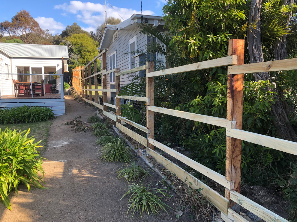 Design ideas for a mid-sized traditional backyard full sun formal garden for spring in Melbourne with with privacy feature and a wood fence.