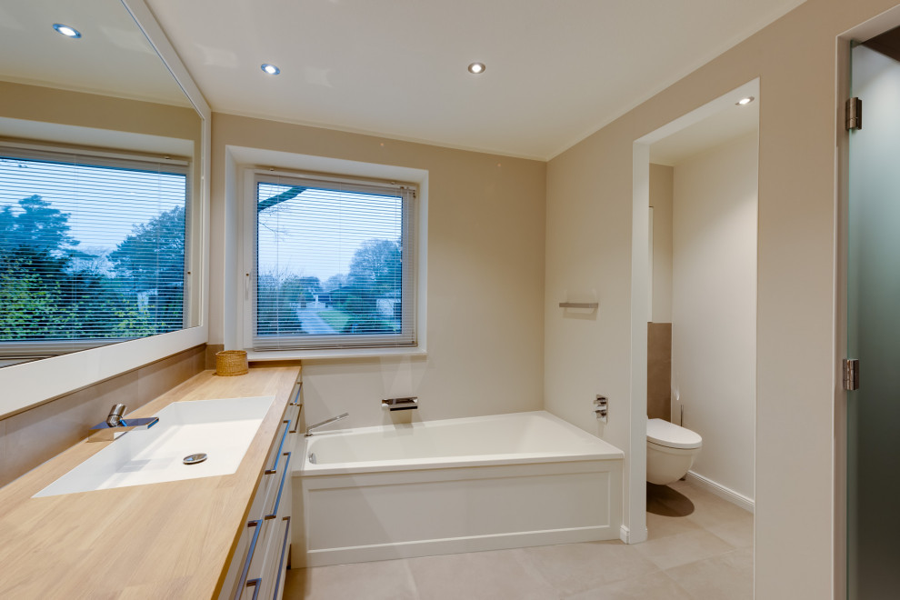 Klassisk inredning av ett mellanstort beige beige badrum med dusch, med luckor med profilerade fronter, vita skåp, ett hörnbadkar, våtrum, en vägghängd toalettstol, vit kakel, beige väggar, ett nedsänkt handfat, beiget golv och dusch med skjutdörr